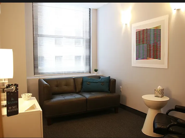 A quiet consulting room with a sofa, chairs and soft window light