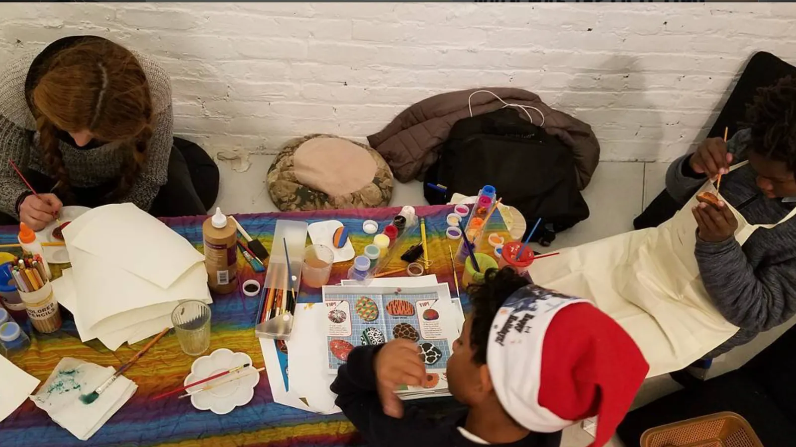 Adults and children painting together around a community outreach activity table