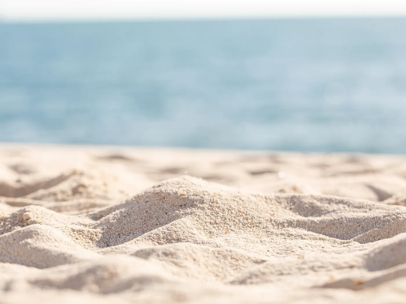 Soft beach sand beside calm blue water