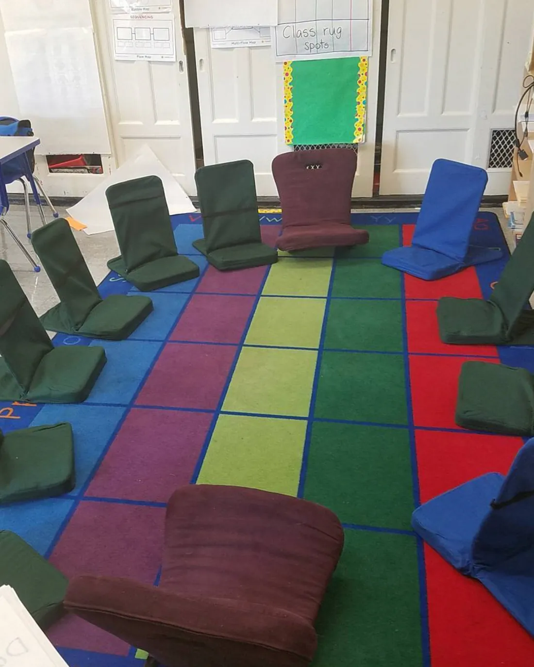 Floor chairs arranged in a circle on a colorful classroom rug for school outreach